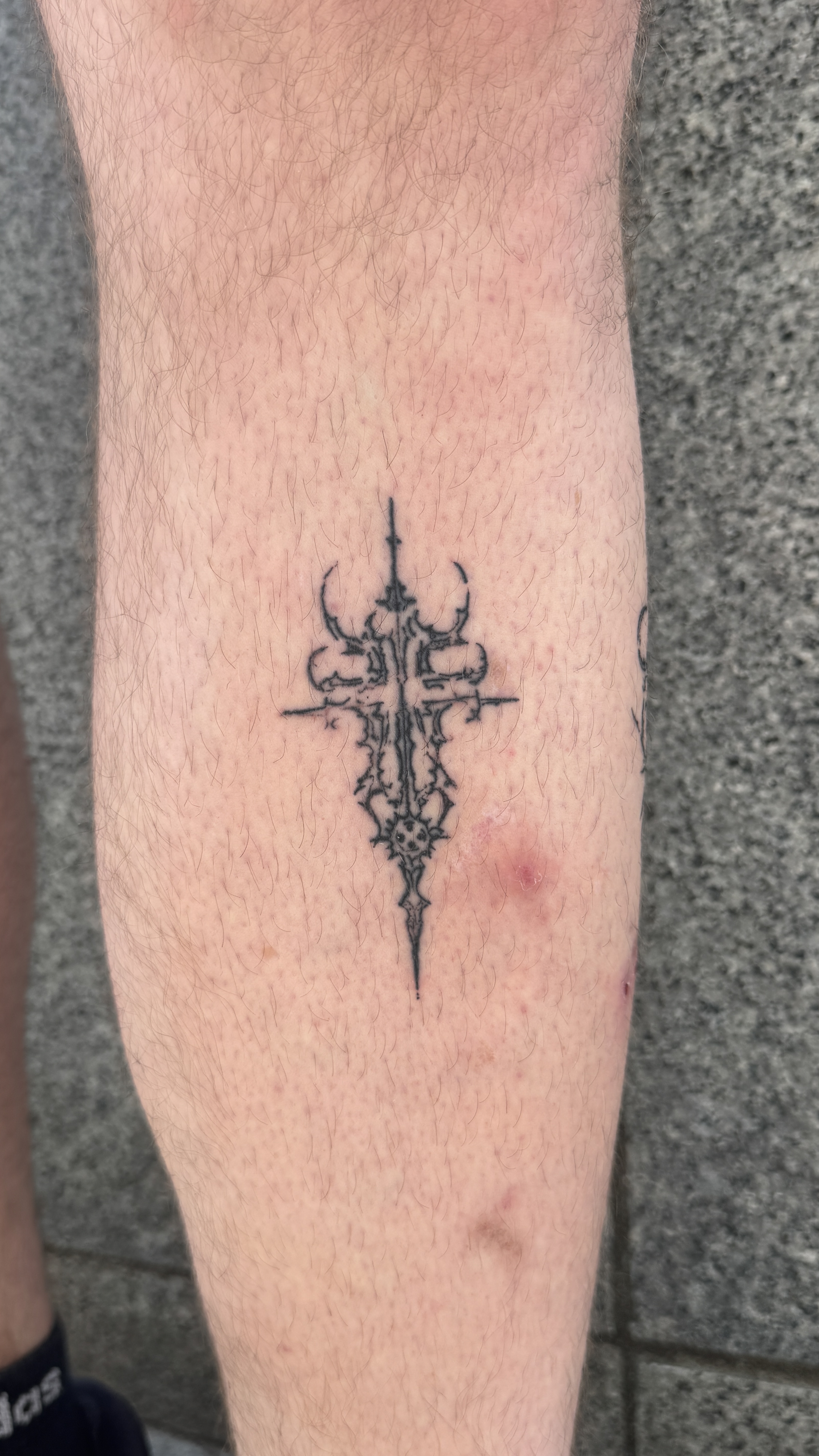 Tatouage fine line croix gothique mollet